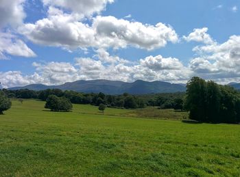 Scenic view of grassy field against cloudy sky