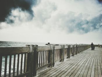 Pier on sea against cloudy sky