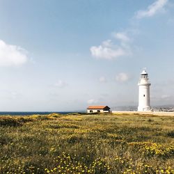 Lighthouse on field against sky