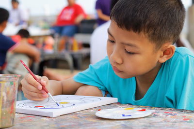 Boy painting on paper at table