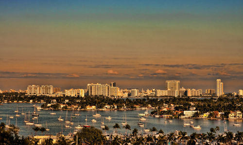 City by sea against sky during sunset