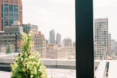 Modern buildings in city against sky seen through window