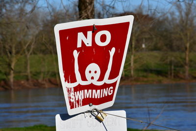 Close-up of warning sign against lake