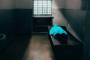 Woman wearing blue raincoat while lying on bed at home