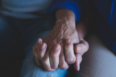 Close-up of couple holding hands at home