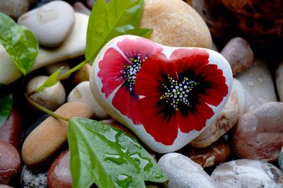 Close-up of heart shape pebble with floral pattern by leaves