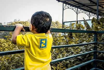 Rear view of boy looking at railing