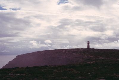 Lighthouse on road amidst buildings against sky