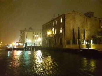 Wet illuminated building against sky at night