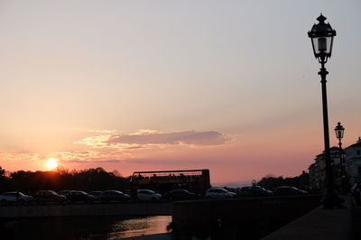 Street light and silhouette buildings against sky during sunset