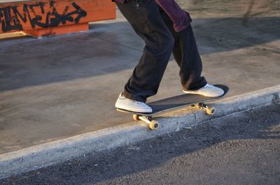 Low section of man skateboarding on road