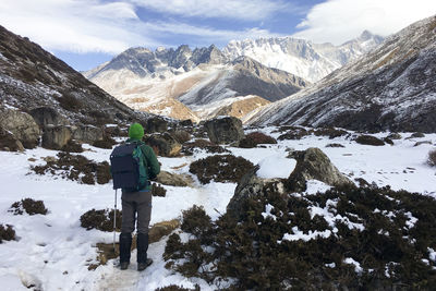 Rear view of man on snowcapped mountains against sky