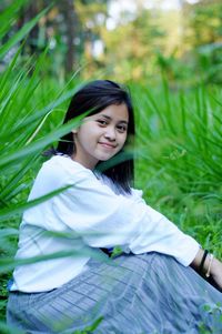 Portrait of a smiling young woman sitting on land