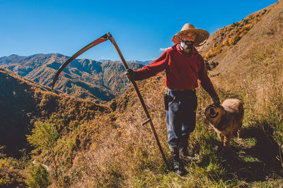 Man with dog standing on landscape against clear sky