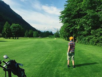 Rear view of teenage boy playing on golf course