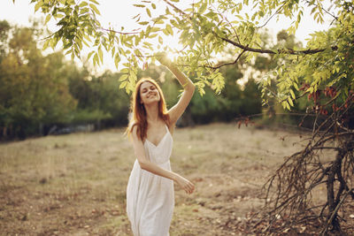 Full length of young woman standing by tree