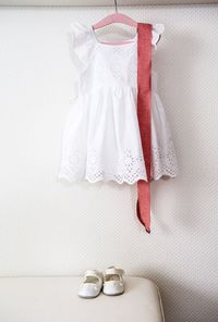Close-up of dress hanging over shoes against white wall