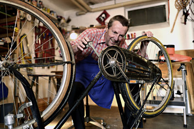 Senior man checking bicycle in his workshop