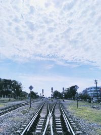 Railway tracks amidst field against sky