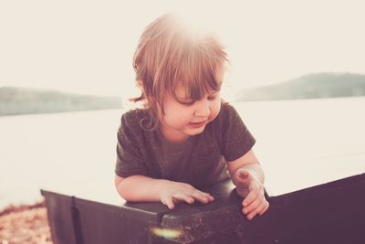 Close-up of boy on table at lakeshore