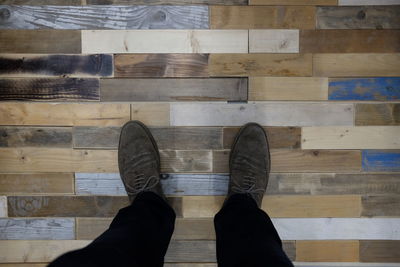 Low section of man standing on hardwood floor