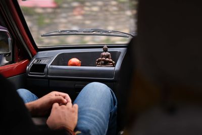 A man on the passenger seat. in front of him there is a small buddha statuette and a fruit.