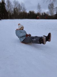 Full length of woman sitting on snow