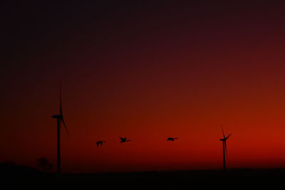 Silhouette of wind turbine against orange sky