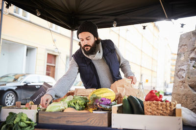 Male vendor arranging vegetables while standing at market stall