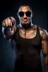 Portrait of confident muscular worker wearing sunglasses while pointing