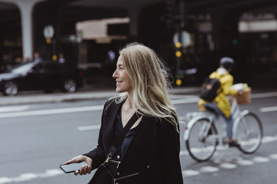 Woman with bicycle on street in city