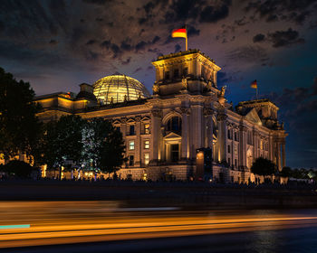 Illuminated reichstag building against cloudy sky at night