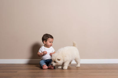 Full length of cute boy with dog on hardwood floor