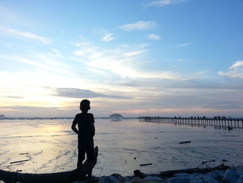 Silhouette man standing on beach against sky during sunset