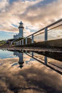 Low angle view of lighthouse against cloudy sky during sunset