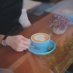 Hand holding coffee cup on table