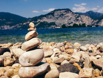 Rocks on sea shore by mountains against sky