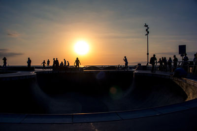 Silhouette people by sea against sky during sunset