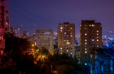 High angle view of illuminated buildings against sky at night