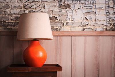 Close-up of lamp on table against wall