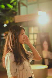 Side view of young woman standing outdoors at night