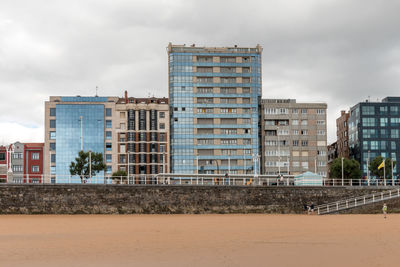 Buildings in city by the beach against sky