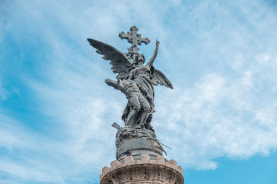 Low angle view of angel statue against cloudy sky