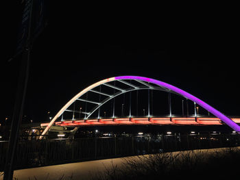 Bridge over illuminated city against sky at night