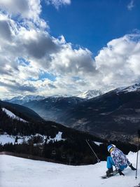 Rear view of man skiing on snowcapped mountains against sky