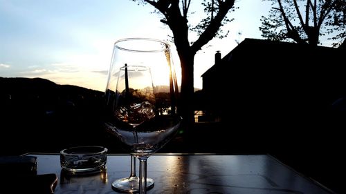 Close-up of beer glass on table against sunset sky