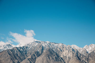 Low angle view of snowcapped mountains against blue sky