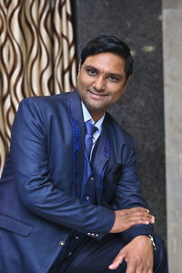 Portrait of smiling young man wearing suit at home