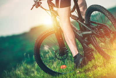 Low section of man riding bicycle on grass