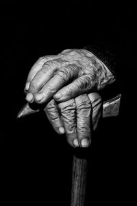 Close-up of senior man hand against black background